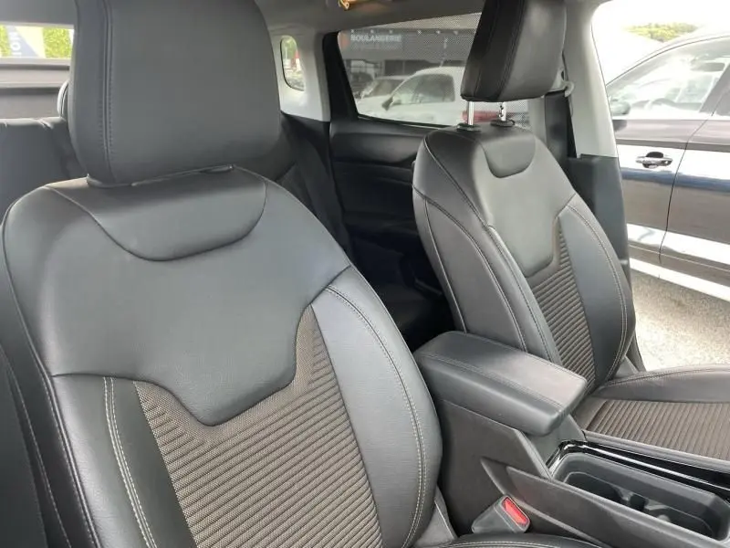 Gros plan sur les sièges avant en cuir noir et tissu du Jeep Compass gris hybride rechargeable 2023, vue intérieure côté conducteur.