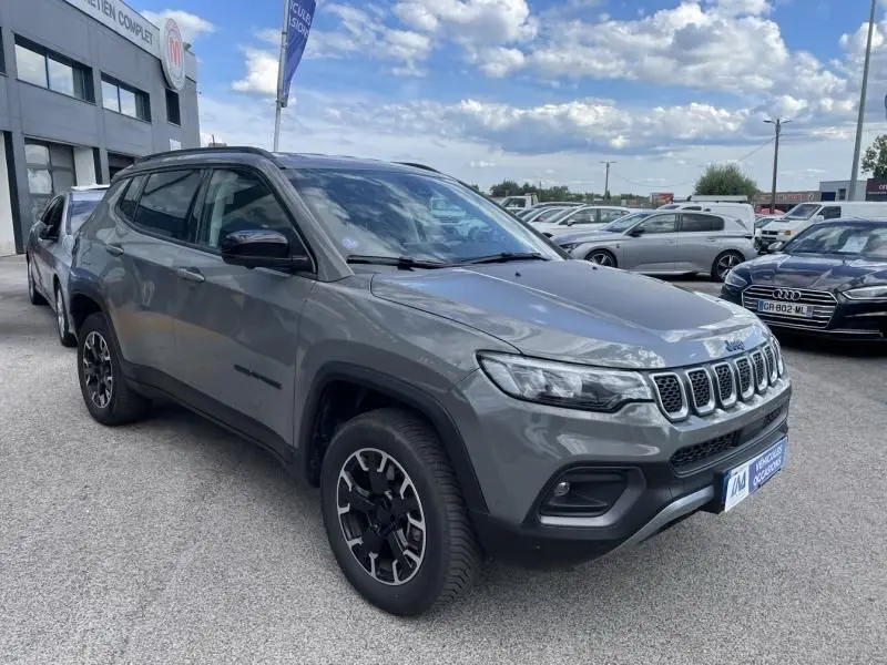 Jeep Compass gris en 3/4 avant droit, avec calandre distinctive à sept fentes et jantes noires bicolores, 2023 hybride rechargeable.