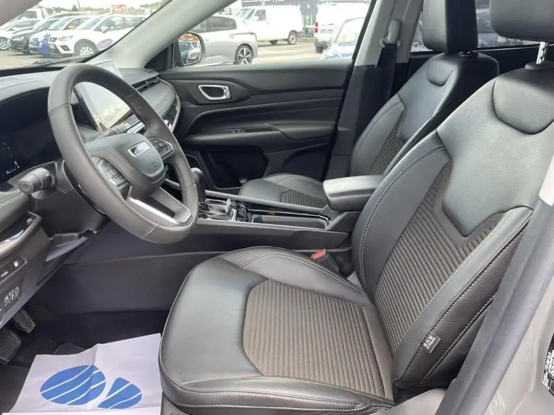 Vue intérieure côté conducteur du Jeep Compass 2023, montrant les sièges noirs en cuir et la console centrale moderne.