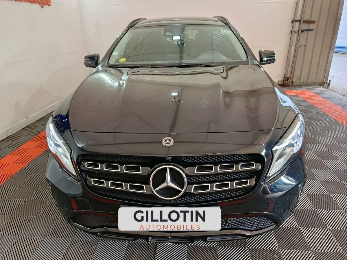 Vue frontale d'un Mercedes GLA 220 d noir brillant avec calandre distinctive et phares LED allumés.