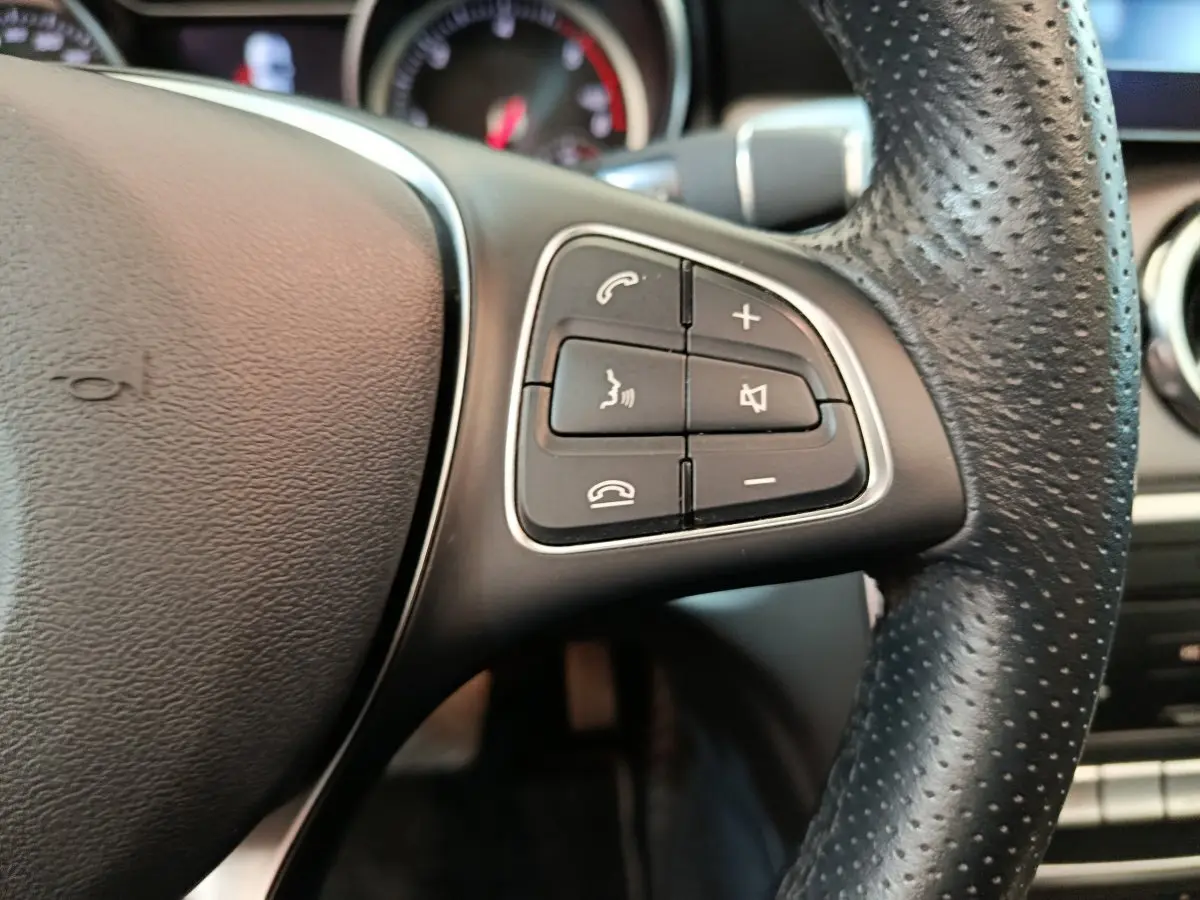 Gros plan sur les commandes du volant cuir perforé côté droit du Mercedes GLA 220 d Business Exec noir de 2018.