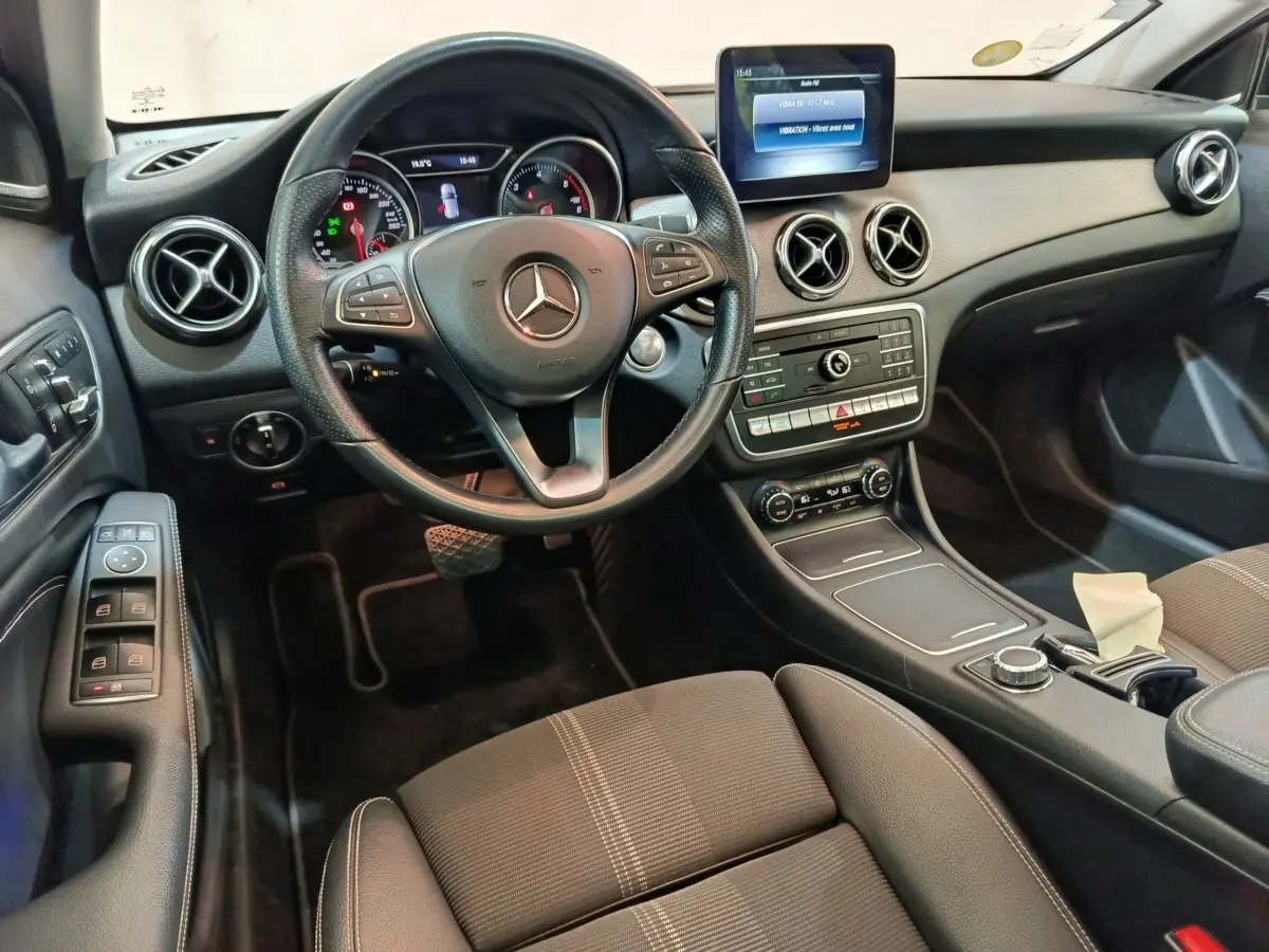 Vue intérieure côté conducteur du tableau de bord noir du Mercedes GLA 220 d avec volant cuir et écran central tactile.