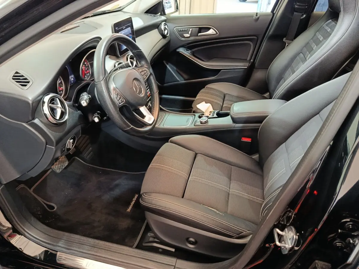 Intérieur noir de la Mercedes GLA 220 d 2018 vu côté conducteur, avec tableau de bord et sièges avant en tissu et cuir.