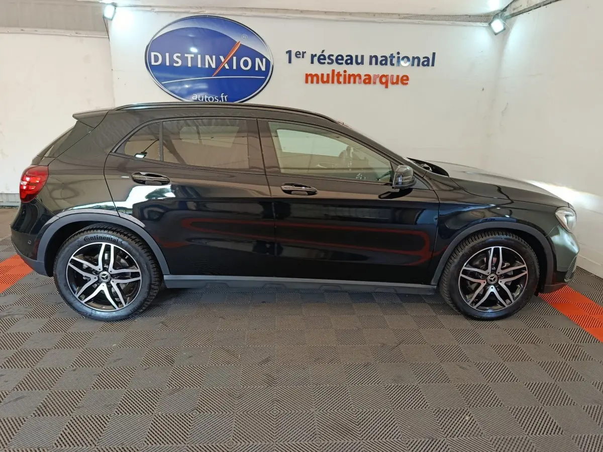 Profil côté droit d'un Mercedes GLA 220 d Business noir, avec jantes alliage et rétroviseurs électriques dans un showroom.