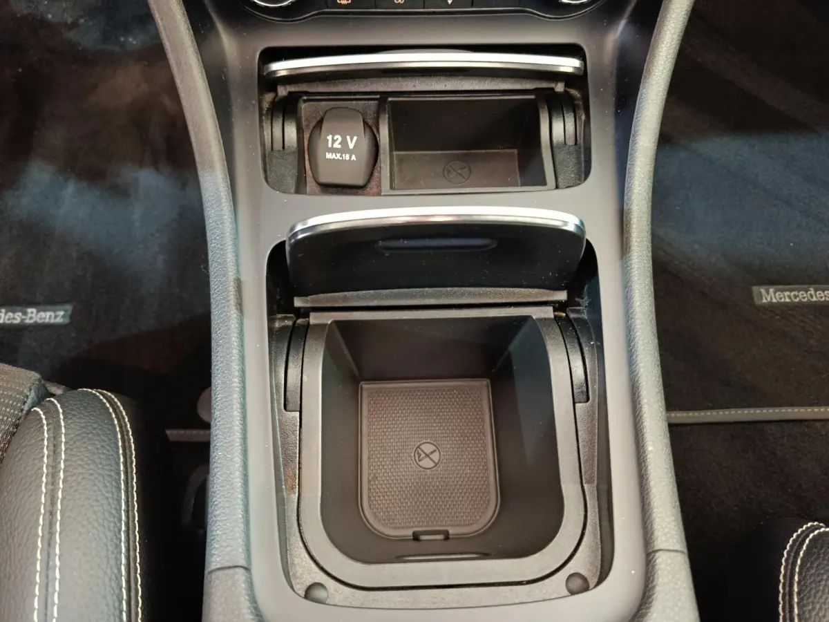 Gros plan sur la console centrale noire du Mercedes GLA 220 d, avec prise 12V et compartiments de rangement ouverts.