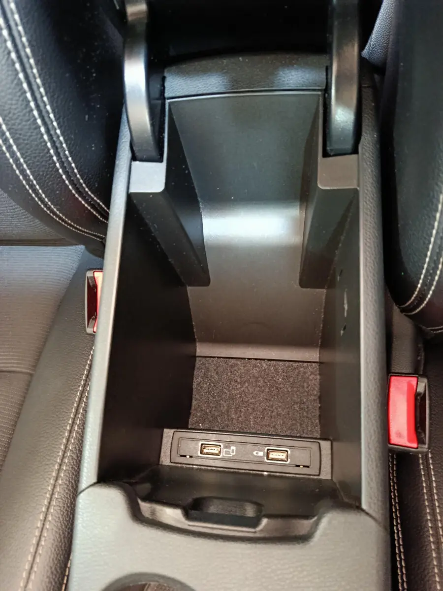 Vue rapprochée de la console centrale noire ouverte du Mercedes GLA 220 d avec ports USB visibles entre les sièges en cuir noir.
