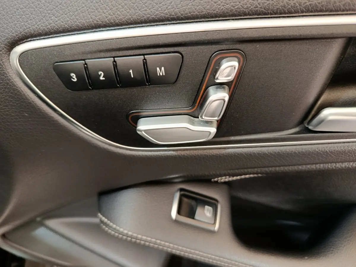 Gros plan sur les commandes de réglage électrique des sièges en cuir noir à gauche dans une Mercedes GLA 220 d 2018.