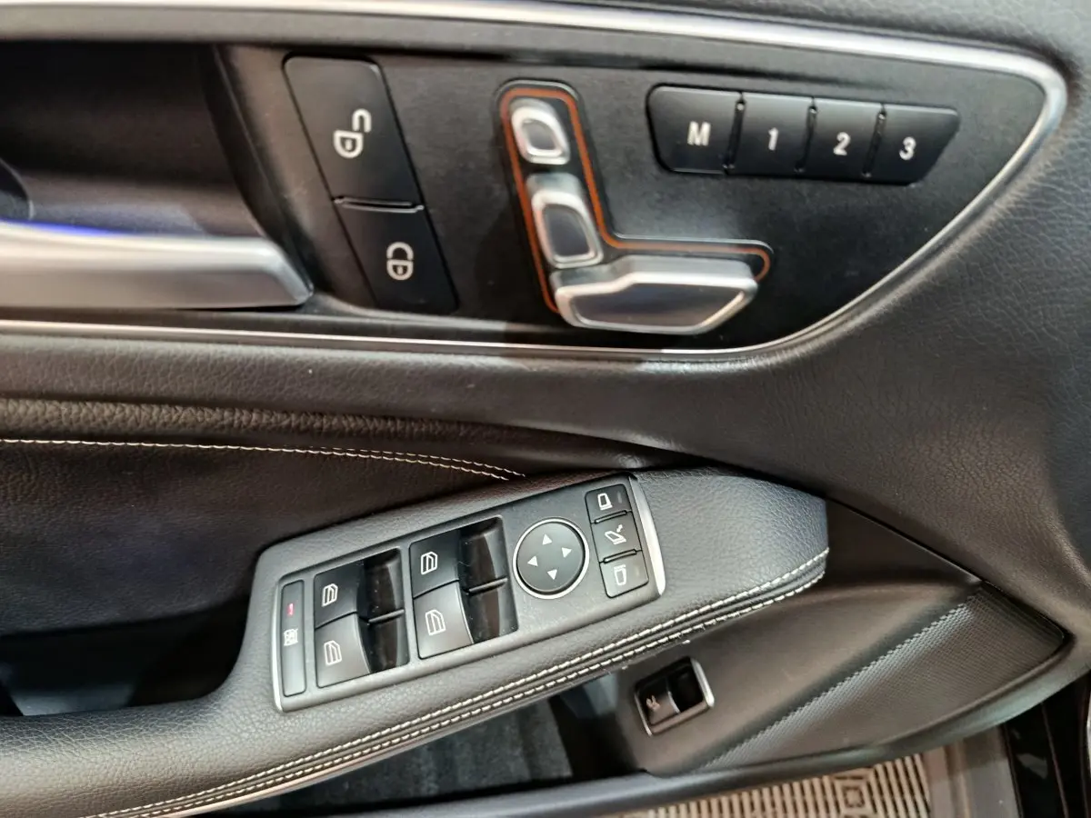 Gros plan sur la porte côté conducteur du Mercedes GLA noir, montrant les commandes des vitres et réglages sièges en cuir noir.