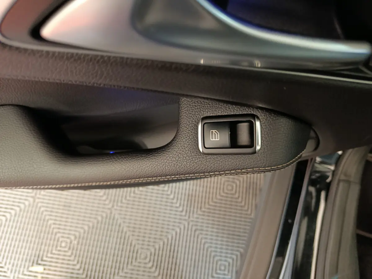 Bouton de commande de lève-vitre sur la porte côté conducteur d'un Mercedes GLA 220 d noir, vue rapprochée intérieure.