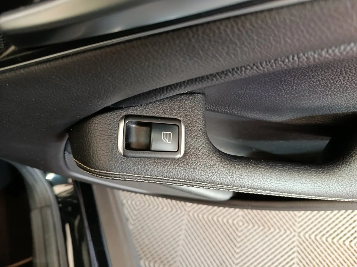 Gros plan sur la commande de lève-vitre en cuir noir sur la portière côté conducteur d’un Mercedes GLA 220 d 2018.