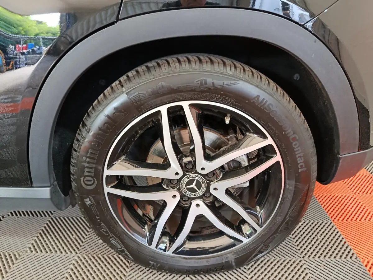 Gros plan sur la roue avant droite noire d’un Mercedes GLA 220 d avec jante alliage cinq branches bicolore.