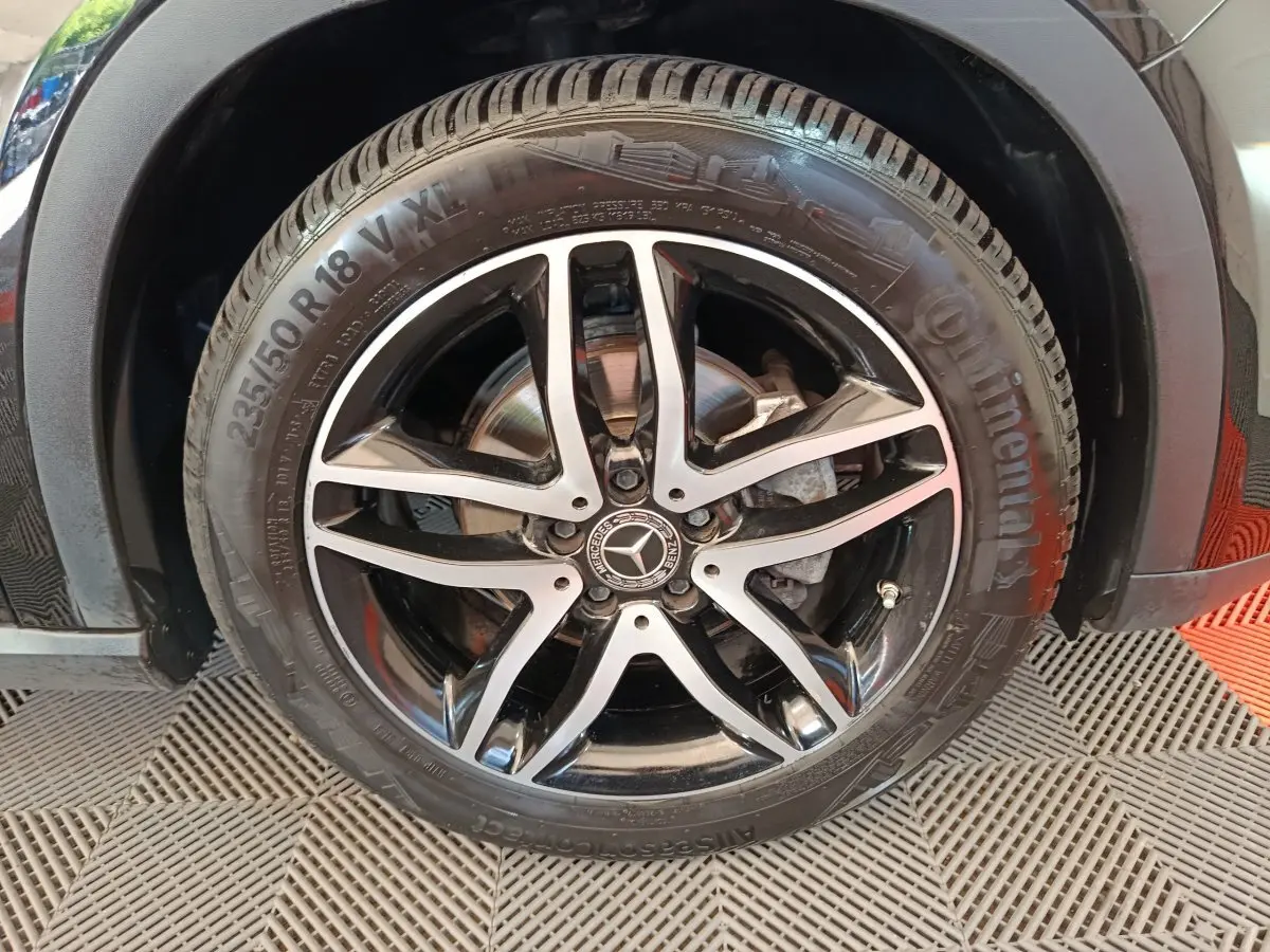 Gros plan sur la roue avant droite noire du Mercedes GLA 220 d avec jante alliage cinq branches bicolore.