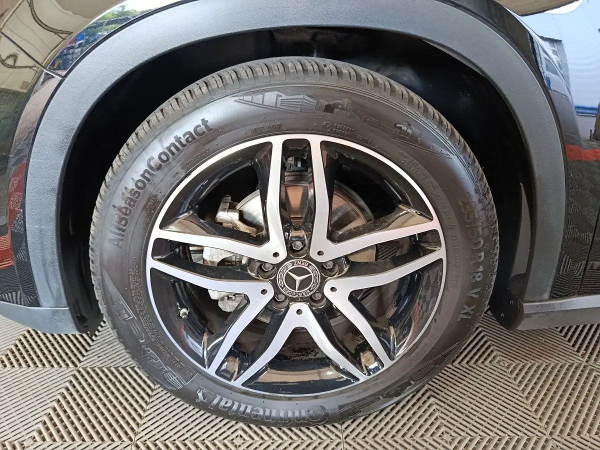 Gros plan sur la roue avant droite noire d'un Mercedes GLA 220 d avec jante alliage cinq branches bicolore.