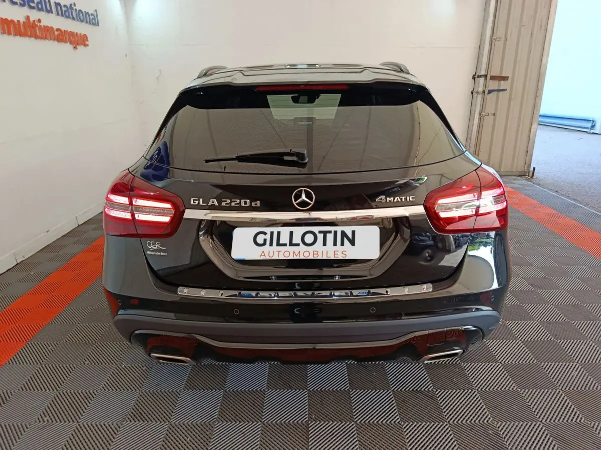 Vue arrière d'un Mercedes GLA 220 d noir avec feux LED et double sortie d'échappement dans un garage.