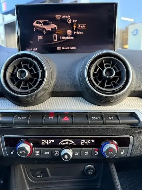 Vue rapprochée du tableau de bord noir de l'Audi Q2 35 TFSI 150 S Line 2023 avec écran tactile et commandes climatisation.