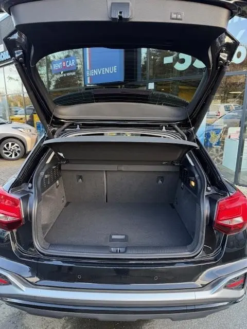 Coffre ouvert d’un Audi Q2 noir 2023 vu de l’arrière, montrant l’espace de chargement et la tablette de séparation.