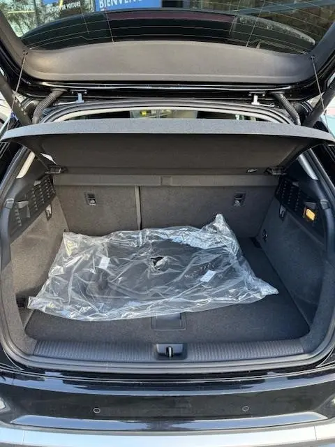 Coffre ouvert d'un Audi Q2 noir 2023, vue arrière, montrant l'espace de chargement avec tapis protégé en plastique.