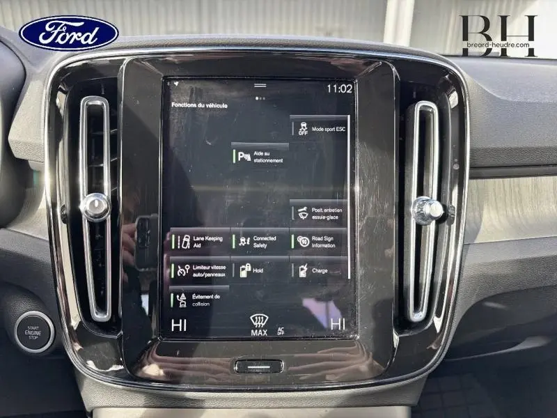 Écran tactile central noir avec affichage des fonctions d’aide à la conduite, entouré de la console intérieure grise.