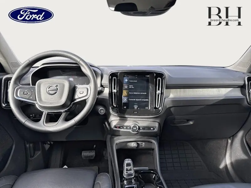 Vue intérieure avant du tableau de bord et volant noir du Volvo XC40 T4 Recharge Bleu Denim, avec écran tactile central.