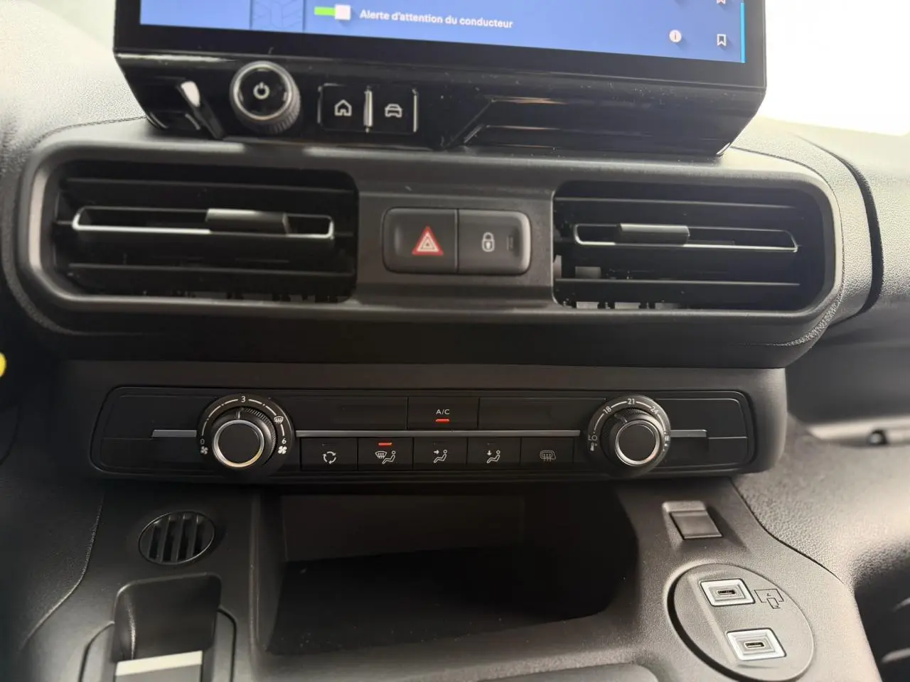 Vue rapprochée de la console centrale noire du Citroën Berlingo 2026, avec commandes climatisation et écran tactile visible.