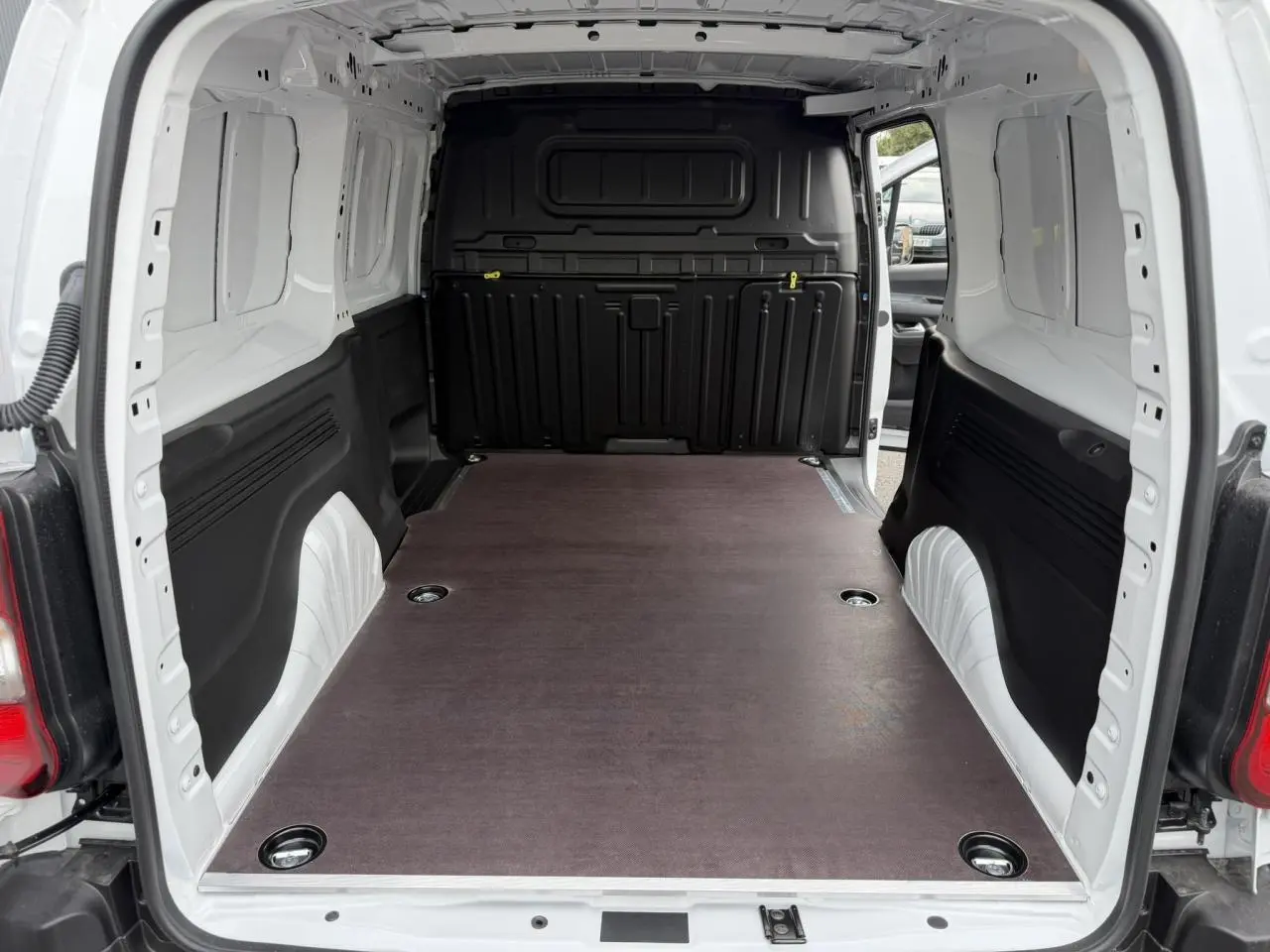 Vue intérieure arrière du Citroën Berlingo blanc Icy avec plancher bois antidérapant et cloison noire.