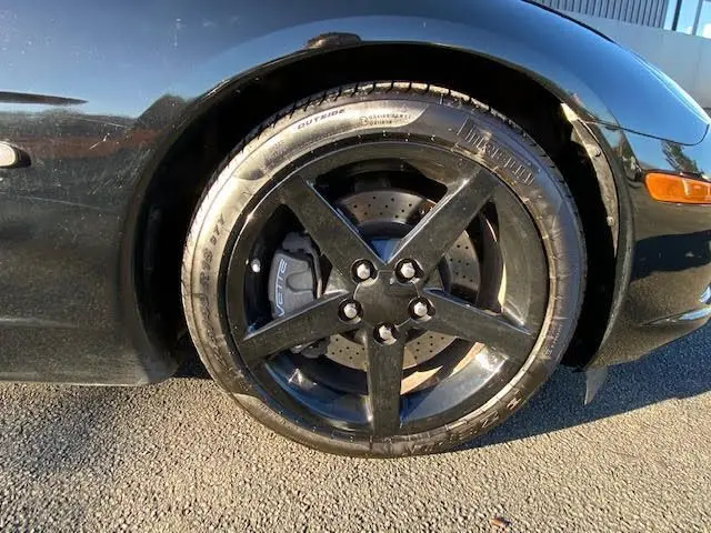 Gros plan sur la roue avant gauche noire d'une Chevrolet Corvette C6 Targa 2005, avec jante cinq branches et étrier marqué Corvette.