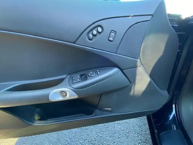 Gros plan sur la porte intérieure côté gauche noire de la Chevrolet Corvette C6 Targa 2005 avec commandes électriques et haut-parleur Bose intégré.