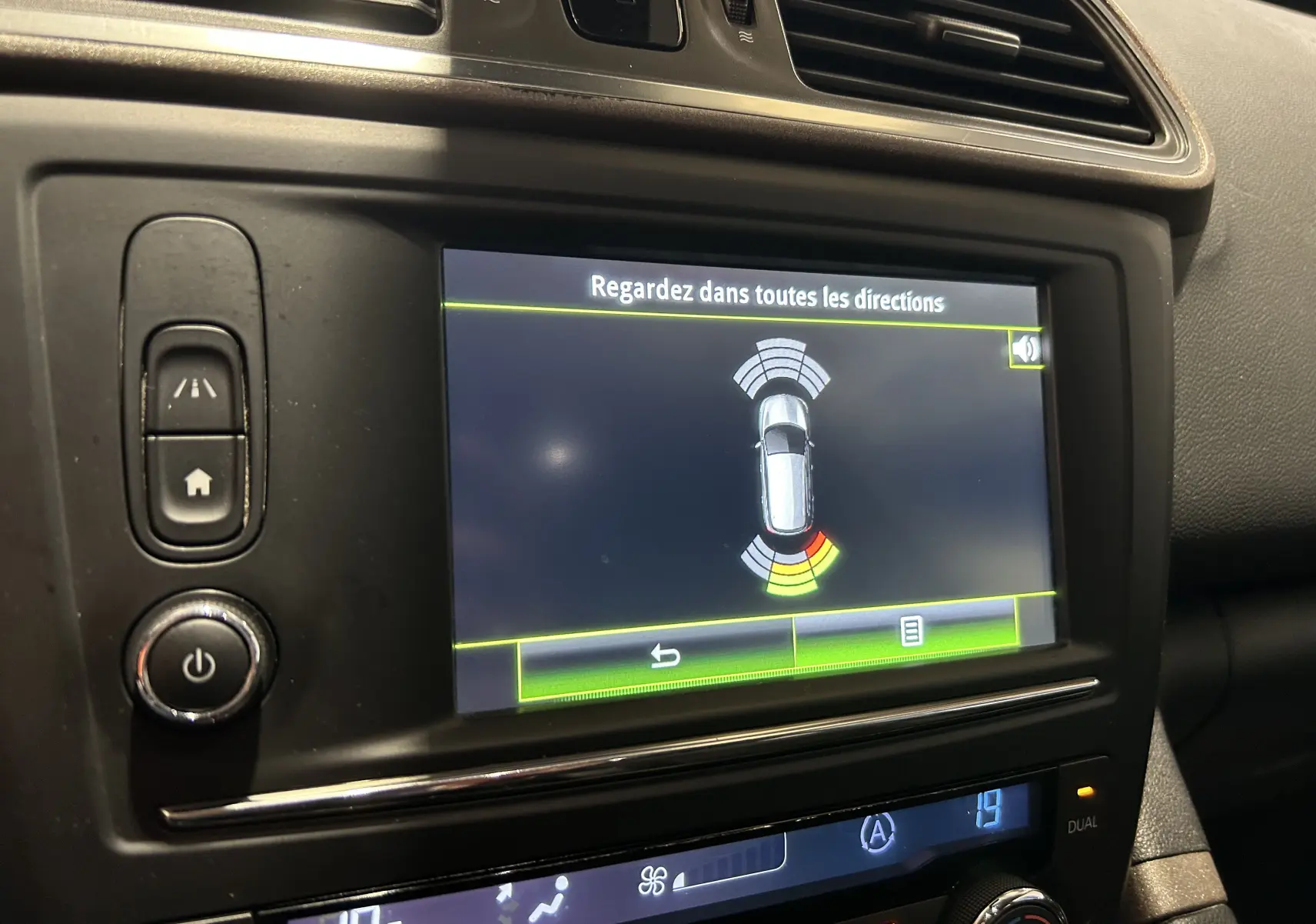 Écran tactile du tableau de bord du Renault Kadjar gris 2015 montrant l'aide au stationnement avec alertes visuelles.