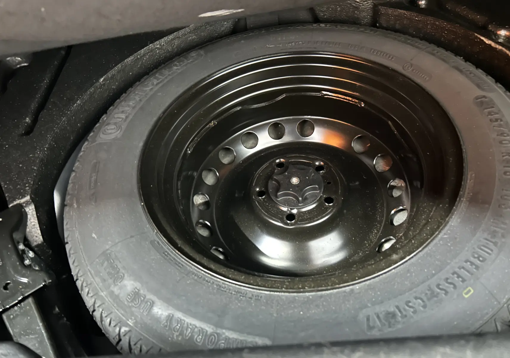 Gros plan sur la roue de secours noire en acier du Renault Kadjar gris, visible dans le coffre du SUV.