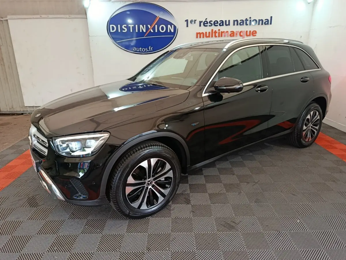 Mercedes GLC 300 e Business Line noir vue 3/4 avant droit, avec jantes alliage et phares LED allumés en intérieur showroom.