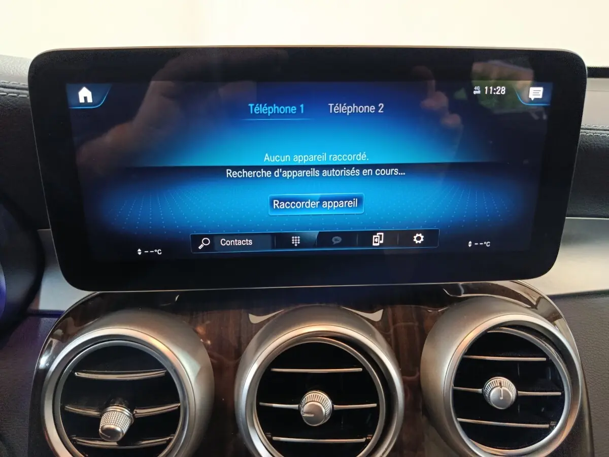 Écran tactile central bleu affichant la connexion Bluetooth, avec trois aérateurs ronds chromés sur tableau de bord noir du Mercedes GLC 300 e.