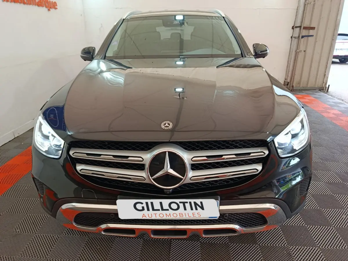Vue avant d'un Mercedes GLC 300 e Business Line noir avec calandre chromée et phares LED allumés.