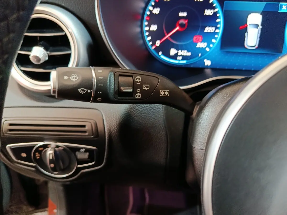 Gros plan sur la commande d’essuie-glace et le tableau de bord numérique bleu d’un Mercedes GLC 300 e noir de 2020.