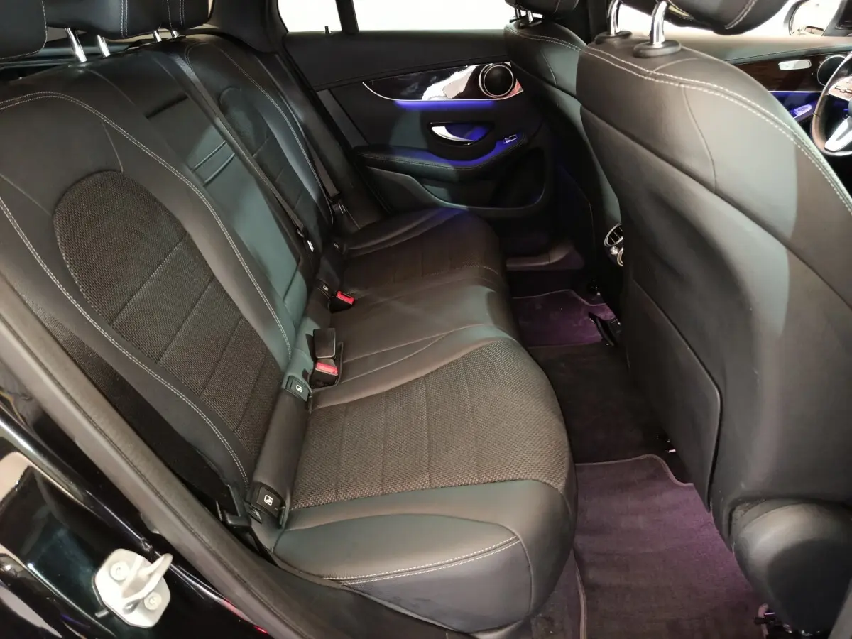 Vue intérieure arrière côté gauche du Mercedes GLC 300 e noir, sièges en cuir noir avec éclairage d'ambiance violet.