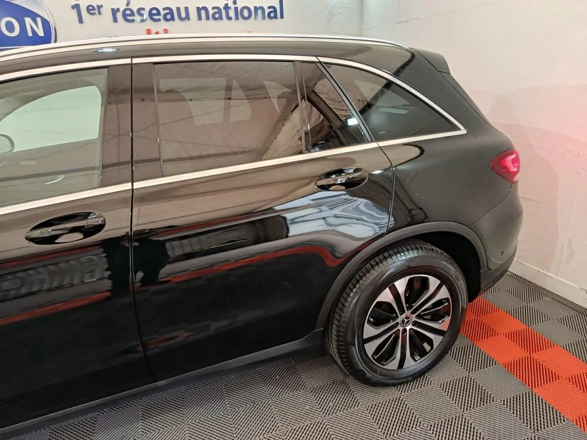 Vue latérale côté droit d'un Mercedes GLC 300 e Business Line noir, mettant en valeur la roue arrière et les lignes élégantes du SUV.