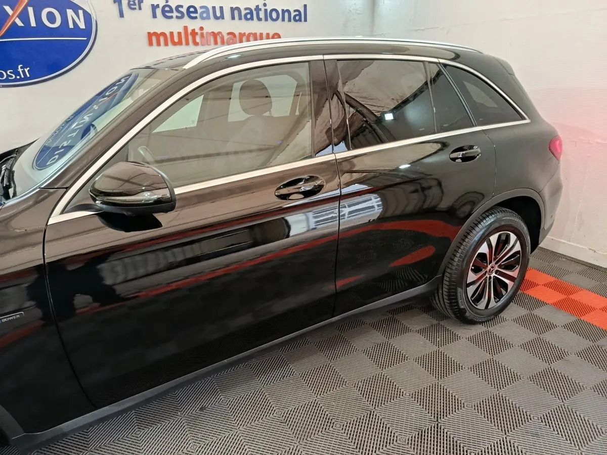 Vue latérale côté gauche d'un Mercedes GLC 300 e Business Line noir stationné en intérieur sur sol damier.