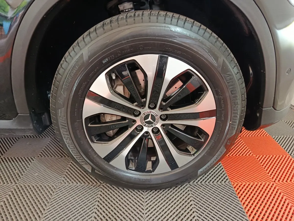 Gros plan sur la roue avant gauche du Mercedes GLC 300 e Business Line noir avec jante alliage bicolore.