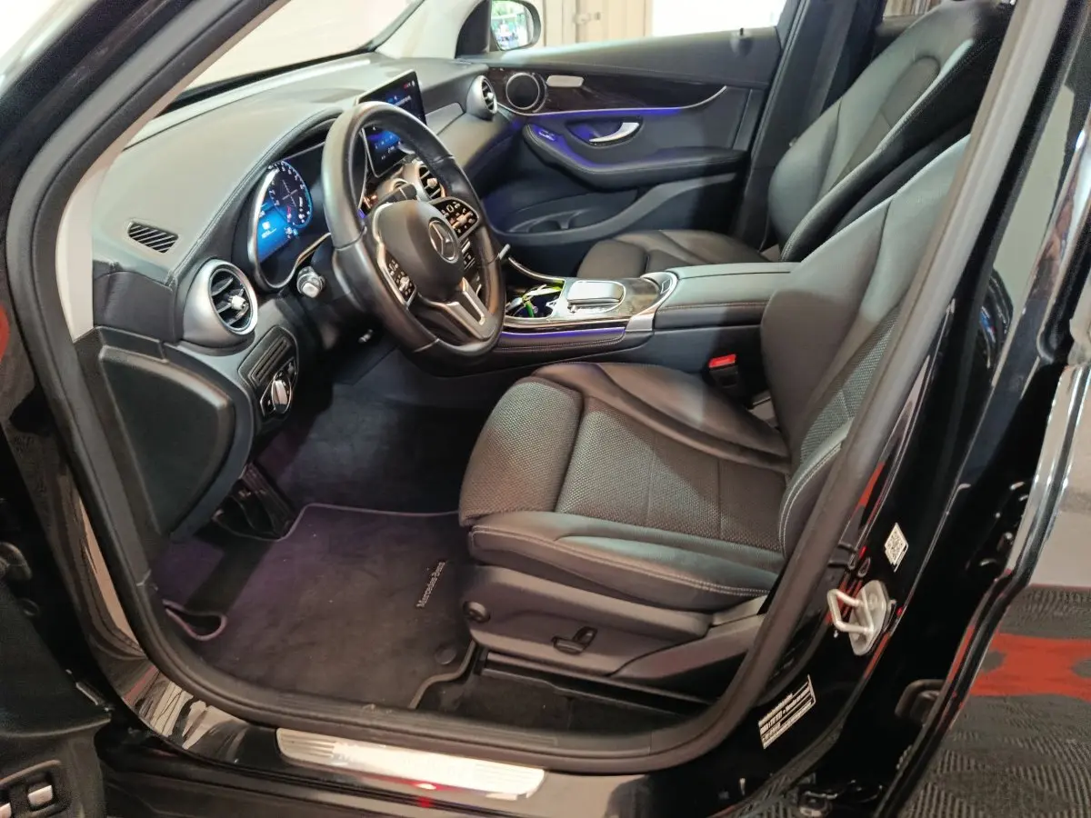 Intérieur côté conducteur d'une Mercedes GLC 300 e Business Line noire, avec tableau de bord digital et sièges cuir noirs.