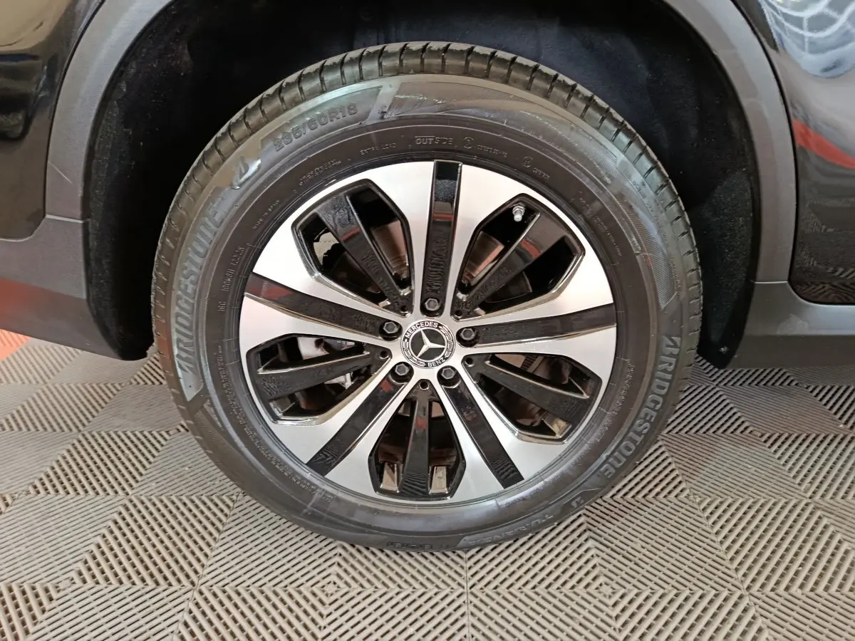 Gros plan sur la roue avant droite d’un Mercedes GLC 300 e noir avec jante alliage bicolore et pneu Bridgestone.