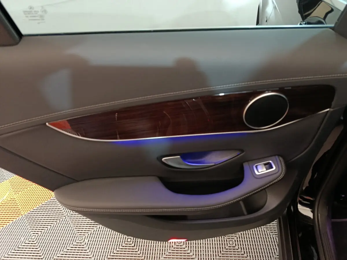 Panneau de porte côté gauche noir avec insert bois et éclairage d'ambiance bleu dans une Mercedes GLC 300 e 2020.