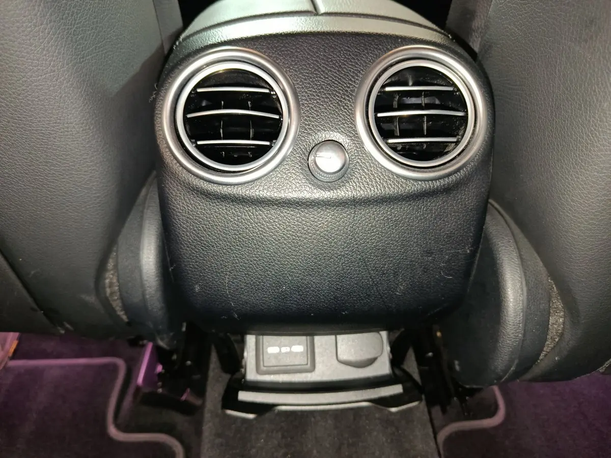 Gros plan sur la console arrière noire du Mercedes GLC 300 e Business Line 2020 avec bouches d’aération rondes et prises USB.