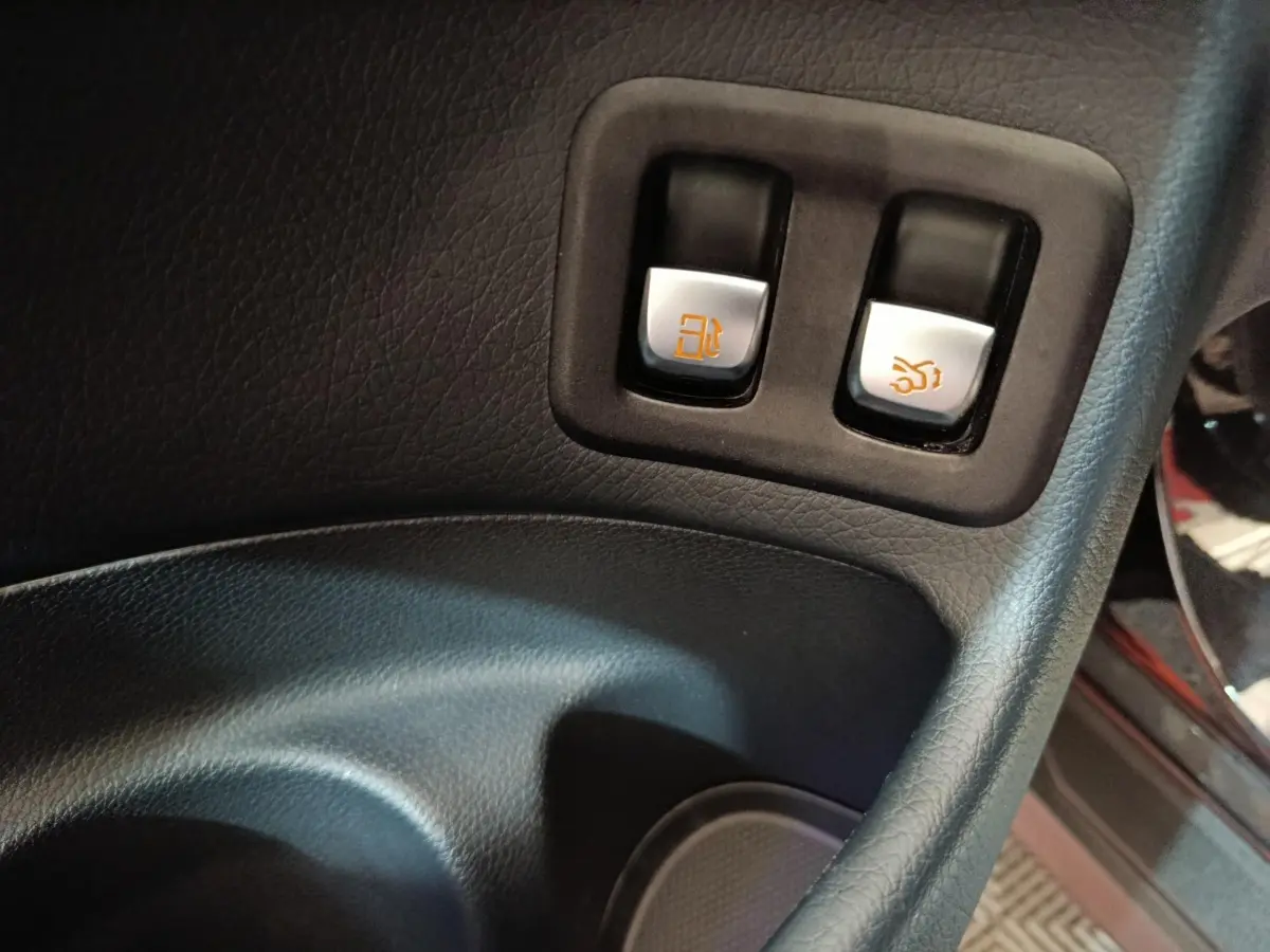Gros plan sur les boutons d'ouverture de trappe carburant et coffre intérieur du Mercedes GLC 300 e noir de 2020.