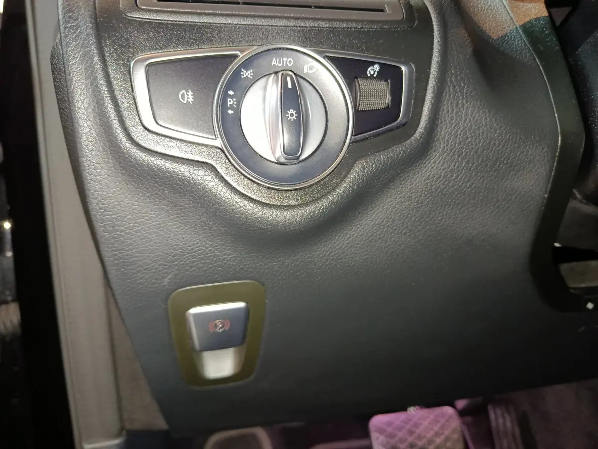 Gros plan sur le panneau de commandes d'éclairage et frein à main électrique du Mercedes GLC 300 e Business Line noir.