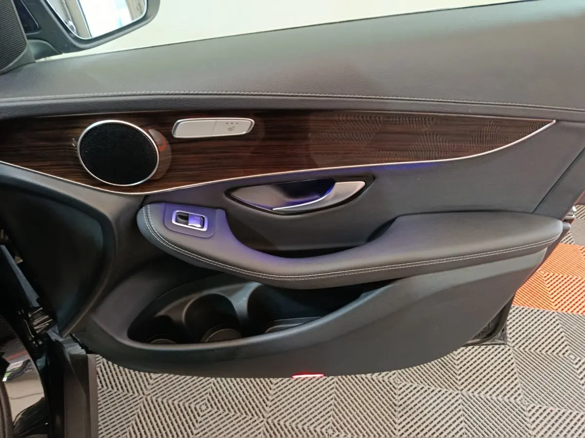 Gros plan sur la porte côté gauche noire du Mercedes GLC 300 e avec insert bois et commande siège chauffant.