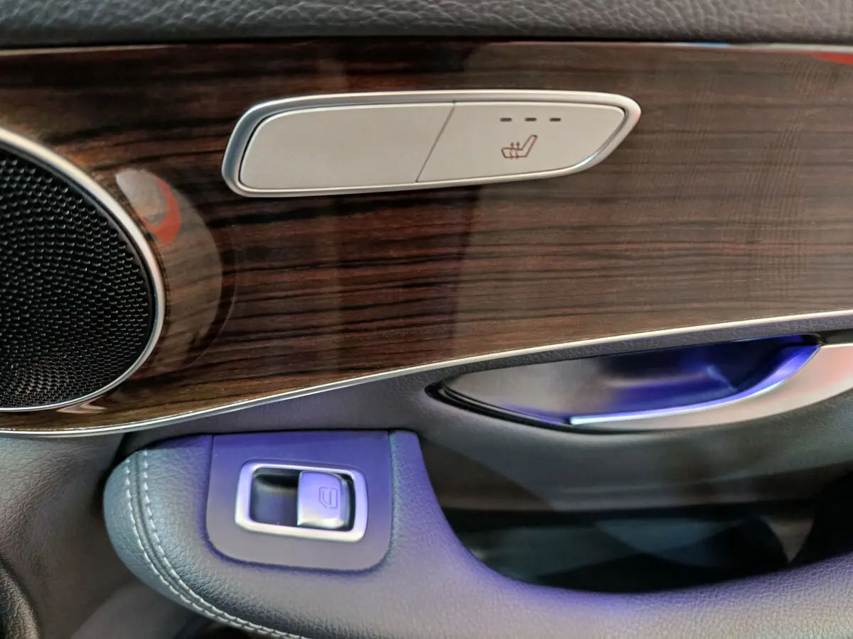 Détail de la portière côté conducteur du Mercedes GLC 300 e noir, avec bois et commandes sièges chauffants.