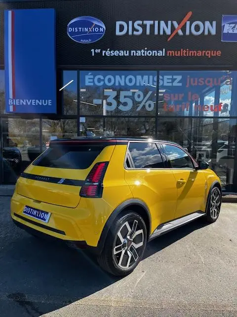 Vue 3/4 arrière droite d'une Renault R5 Techno jaune électrique stationnée devant une vitrine avec enseigne Distinxion.