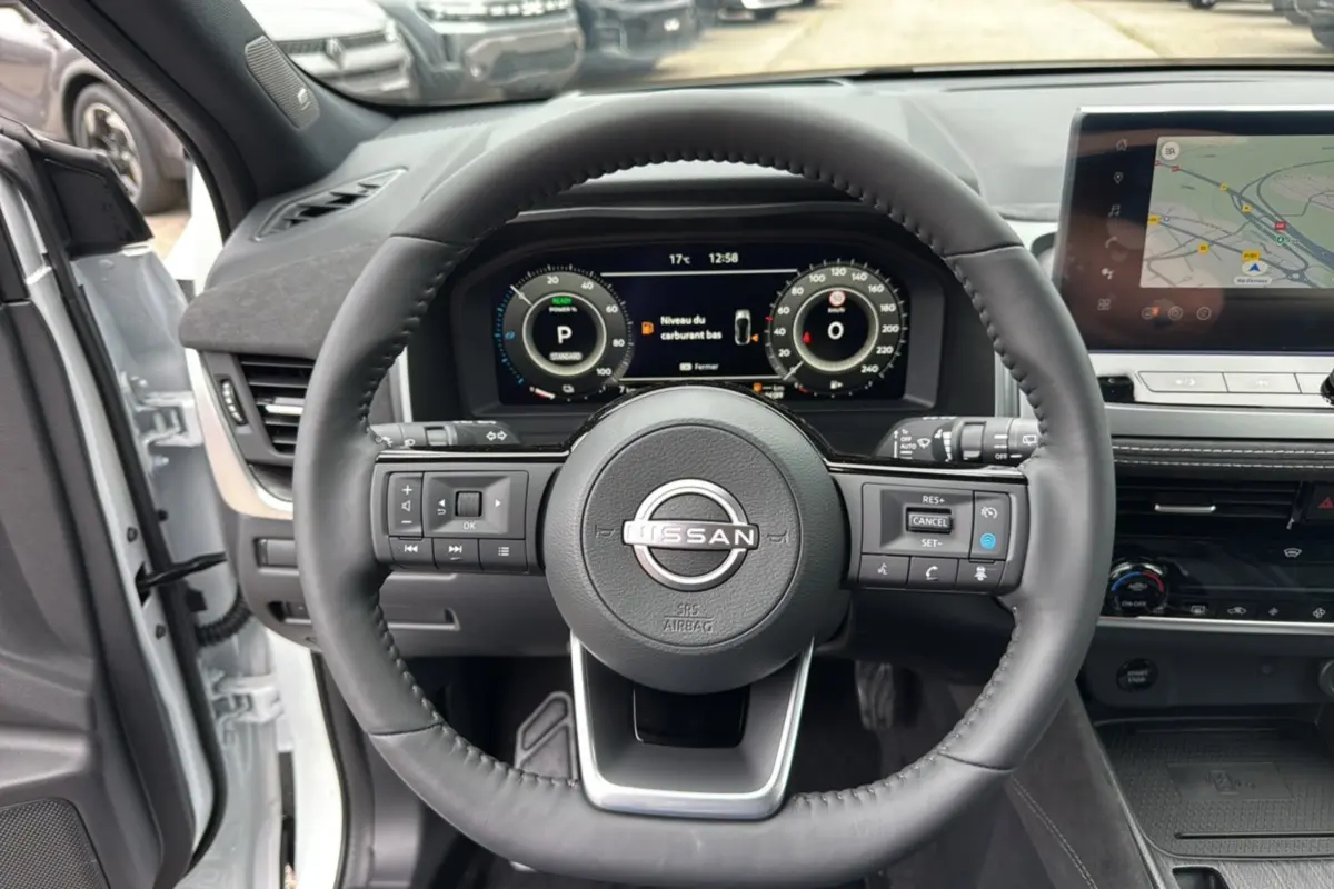 Vue centrée sur le volant cuir noir du Nissan Qashqai E-Power 205 Tekna Plus avec tableau de bord digital et écran GPS.