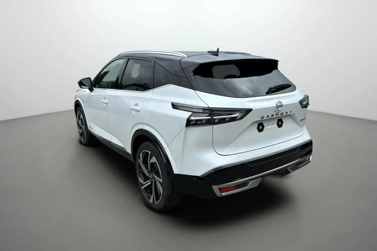 Vue 3/4 arrière droite du Nissan Qashqai blanc lunaire avec toit noir et jantes alu 20 pouces dans un studio.