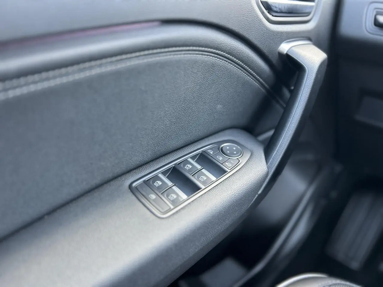Gros plan sur la commande des vitres électriques côté conducteur du Renault Captur 2024, intérieur noir texturé.