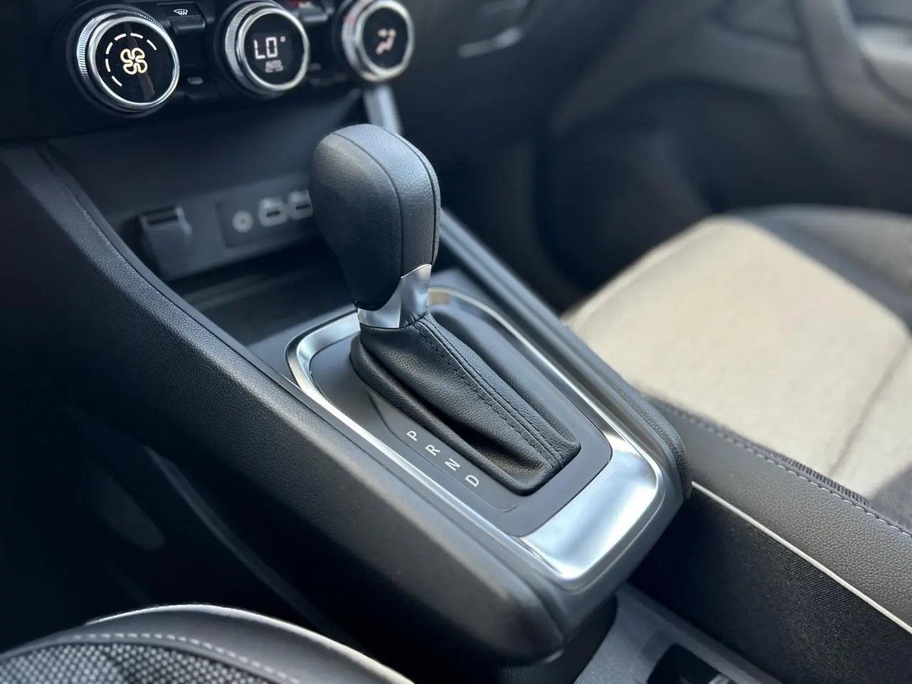 Gros plan sur la commande de la boîte automatique du Renault Captur 2024, avec sellerie claire et console noire.